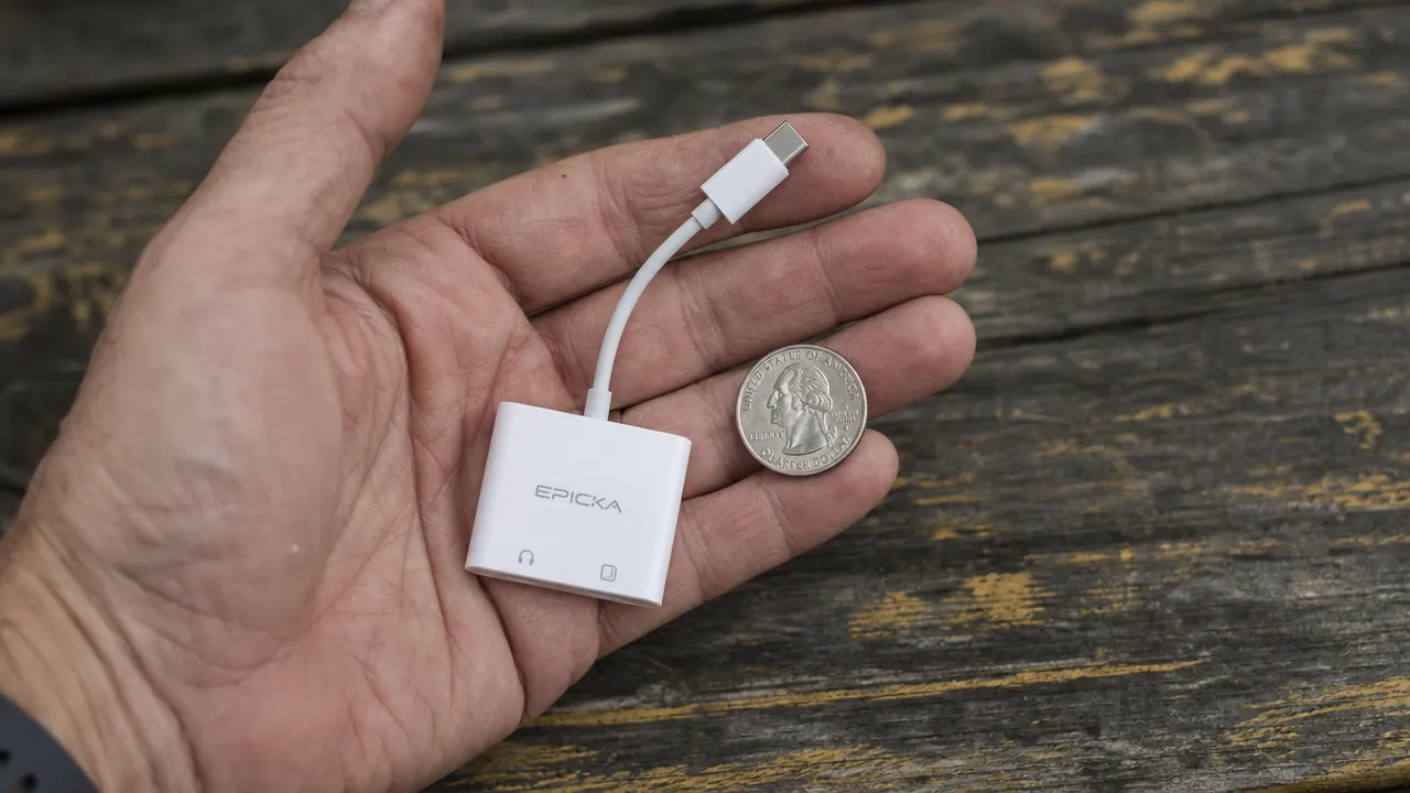 Hand holding the EPICKA adapter next to a quarter coin showing its compact size